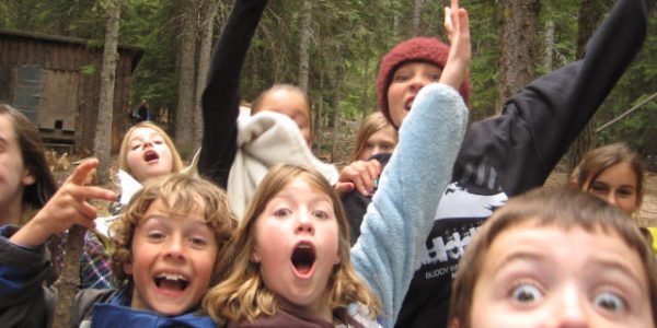 Excited kids outdoors raising hands