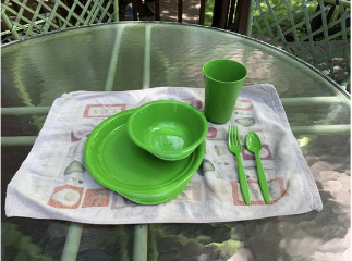 Green reusable dishware arranged on a picnic table