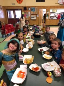 Students sitting with food in a school cafeteria looking at camera