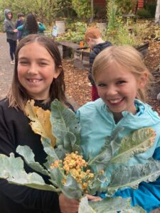 two young girls smile holding a cauliflower plant