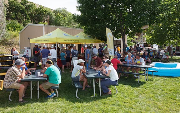 A group of people eating at picnic tables with some booths in the background