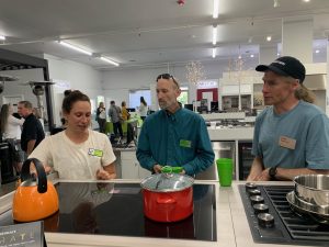 three people gather around an induction stove in a showroom