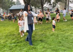 A group of people outside on a grass lawn with some students following a teacher