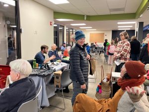 A room full of people, some sitting in chairs waiting, others behind tables fixing items