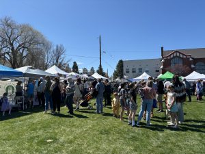 Field with green grass and white vendor tents, with families mingling.