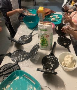 Childrens hands making home made tortillas with corn meal and water. Balling up the corn paste and pressing it with caste iron tortilla presses.