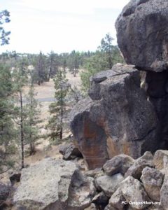 large boulders overlooking a canyon with pine trees in the background