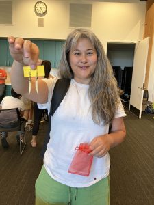 person with long hair holding up earrings