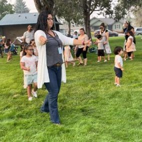 A group of people outside on a grass lawn with some students following a teacher