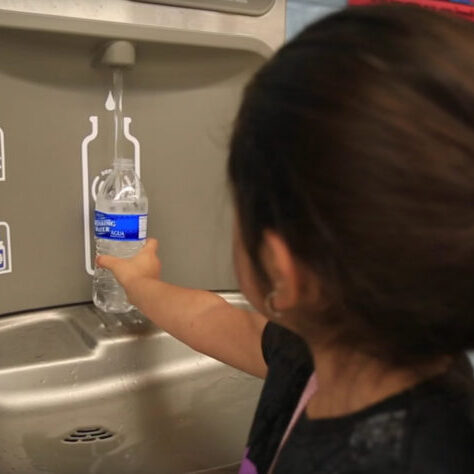 Student filling a water bottle at a refill station